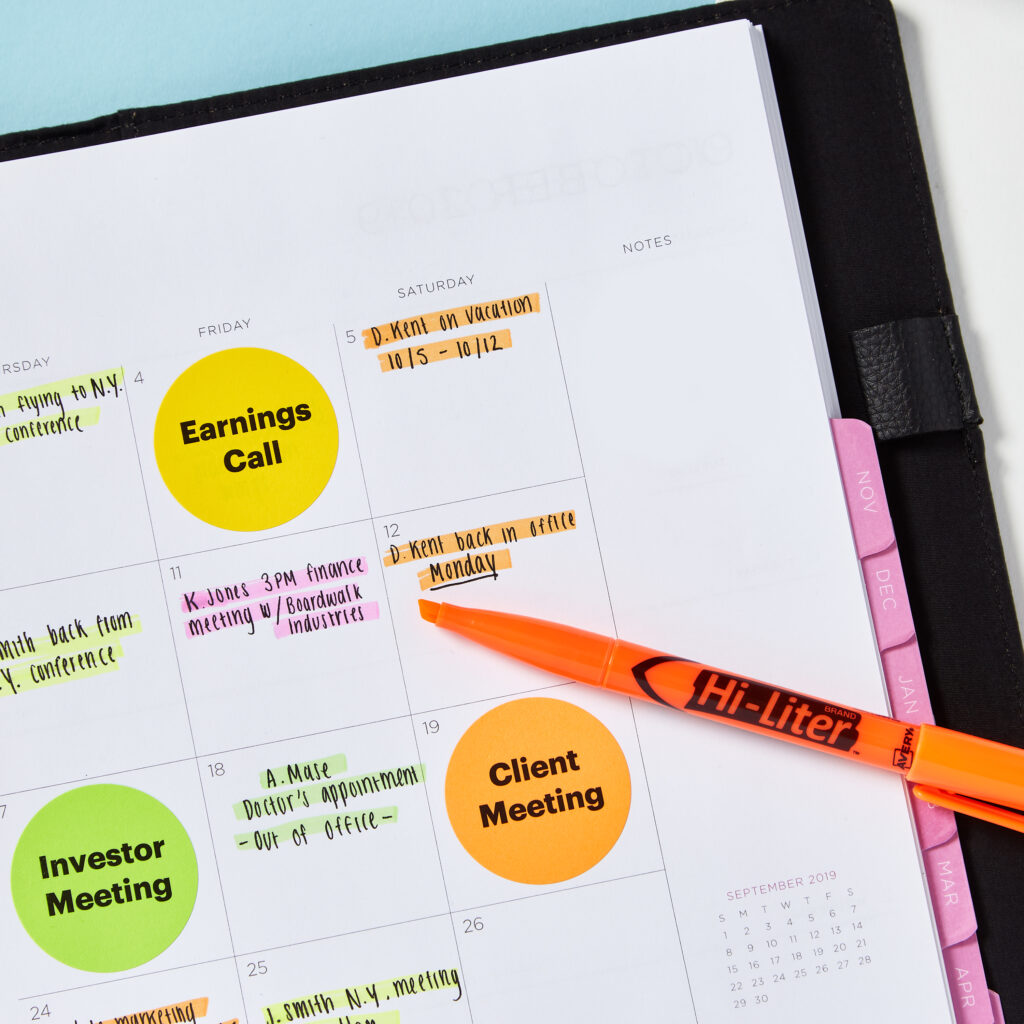 A calendar layout featuring Avery 5474 round neon labels highlighting key events such as "Earnings Call," "Investor Meeting," and "Client Meeting." Handwritten notes and bright highlighter accents emphasize important dates and tasks. An orange Hi-Liter rests on the page, complementing the vibrant labels and color-coded organization. The layout provides a clear and visually striking method for tracking appointments and deadlines.